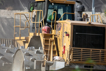 A Heavy, Steel Wheeled, Bulldozer Tractor at a Sanitary Landfill Pushing Trash into the Slope to be Covered by Dirt to make Room for more Refuse
