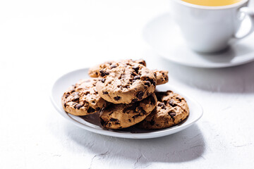 Cup of tea in white cup with chocolate chip cookies as a part of a scene, on a white background