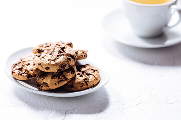 Cup of tea in white cup with chocolate chip cookies as a part of a scene, on a white background