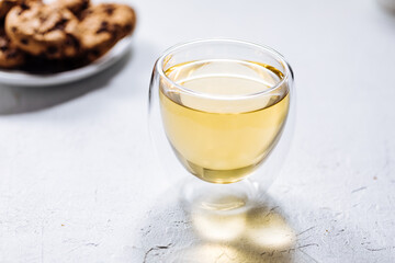 Cup of tea in white cup with chocolate chip cookies as a part of a scene, on a white background