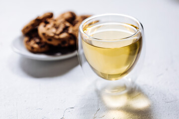Cup of tea in white cup with chocolate chip cookies as a part of a scene, on a white background