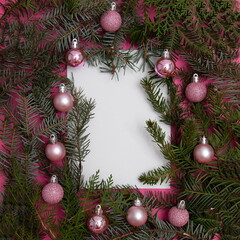 Fototapeta na wymiar Evergreen trees with Christmas tree decorations on a pink background with copy space in white. Flat lay minimal scene.