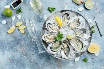 Fresh opened oysters in a plate with ice and lemon on blue background, Healthy food, gourmet food. Oyster dinner in restaurant. top view