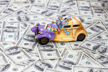 A miniature ceramic car stands on dollar bills