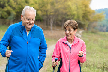 Happy senior couple trekking together having fun outdoor in the woods - Focus on woman face