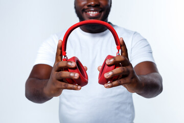 A nice-looking professional model is holding red bluetooth headphones in front of camera.