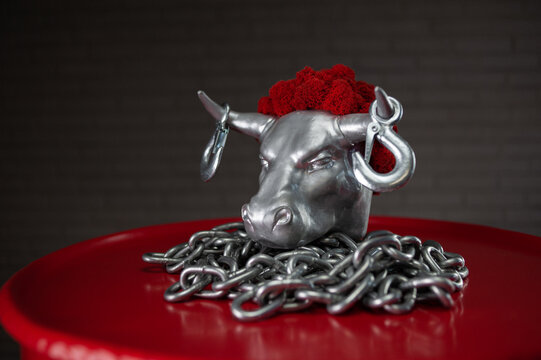 figurine of a bull's head with transportation hooks on horns and a metal chain