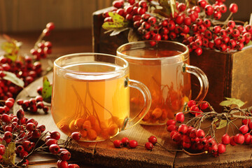 Haw thorn berry tea in a  glass cup on rustic background, red herbal tea is a cardiovascular drink...