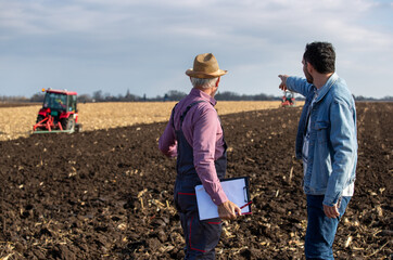 Farmers talking in field in front of tractor