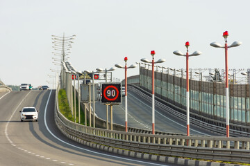 Expressway and ascent to the bridge with a speed limit sign under the glide slope path marked with...