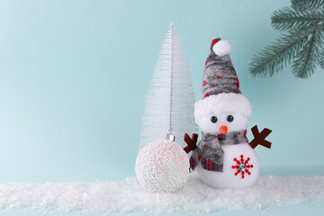 Snowman, gift, Christmas tree, Christmas ball on white snow on a turquoise background. Christmas New Year card. Place for an inscription.