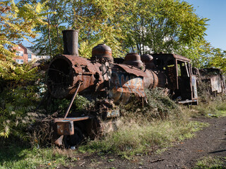 Steam locomotive MSP (Ponferrada steel miner) in very bad condition, completely rusty and rusty abandoned on the unused tracks and covered by vegetation that has run its course in the city 