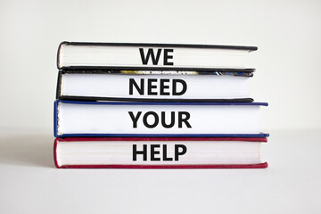 We need your help symbol. Books with concept words 'We need your help'. Businessman hand. Beautiful...