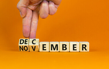 Symbol for the change from November to December, winter. Businessman turns wooden cubes and changes the word 'November' to 'December'. Beautiful orange background, copy space. Happy December concept.