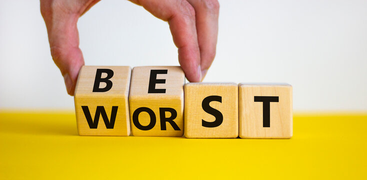 Best or worst symbol. Businessman turns wooden cubes and changes the word best to worst. Beautiful yellow table, white background, copy space. Business and best or worst concept.