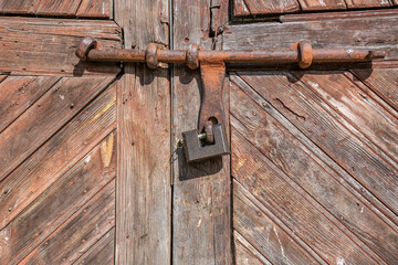 
Old wooden gate closed on a rusty bolt with a lock