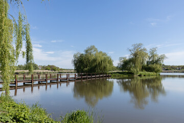 Fototapeta na wymiar Spring landscape with wooden bridge over the river