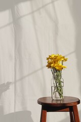 Yellow flowers in a glass jar creating shadow on a white wall