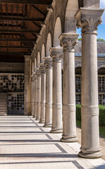 Corinthian columns in a raw with their shadows reflecting on the floor under a bright sunny day.