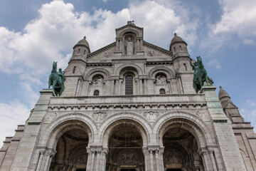 Fototapeta na wymiar The entrance of the Sacre Coeur Basilica( Basilica of the sacred heart) with the two bronze statues of King Saint Louis on the left and Saint Joan of Arc on the right. 