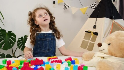 Cute girl kid vlogger sit at table recording vlog for social media blog with fluffy bear and toy colorful plastic construction blocks. Weekend leisure playtime activity, blogger, playthings store ad - Powered by Adobe