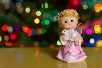 figurine of an angel on a background of Christmas tree lights bokeh copy space