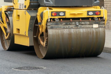 Laying of new asphalt on a city street. Large equipment for laying and tamping asphalt is working on the road. The use of a roller when laying asphalt ensures absolute evenness of the coating.