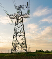 silhouette of high voltage power lines against a colorful sky at sunrise.