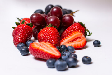 Fototapeta na wymiar Mix de frutos, arándanos, frutillas y uvas sobre fondo blanco 
