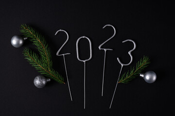 Figures for the upcoming new year 2023 with fir ropes and silver Christmas balls. Flat lay