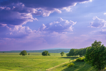 Violet-blue clouds and green fields.
