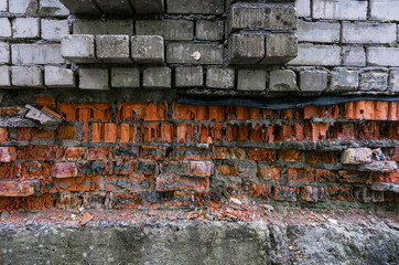 Broken old white and red brick wall with wide hole front view.