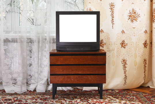 Old TV with white screen on a vintage wooden cabinet, old design in an apartment in the style of the 1980s and 1990s. Interior in the style of the USSR.
