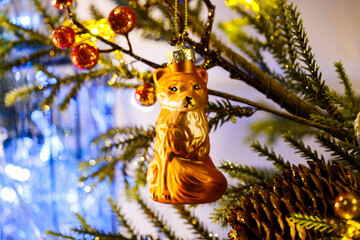 Christmas tree toys close-up. A glass fox hangs on the branches of a decorative Christmas tree