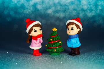 New Year's idea. Figurines of children at the Christmas tree on a blue background. Holiday Toys