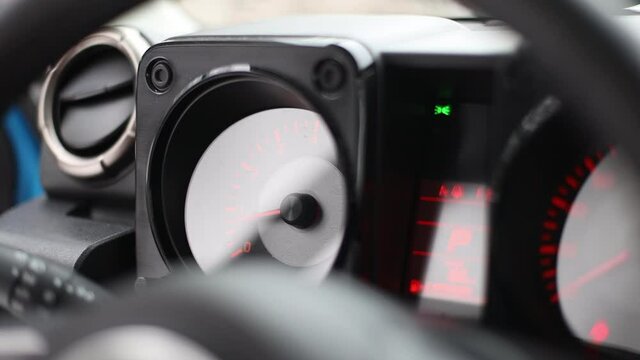 analog tachometer in a modern car with red arrows and numbers