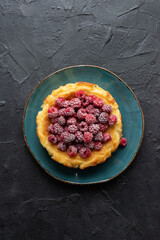 Raspberry homemade cheesecake on turquoise plate with dark plaster background