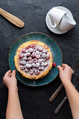 Kid hold homemade raspberry cheesecake with icing on turquoise plate with coffee cups