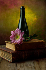 still life of antique books, flower, and wine bottle against textured background © Robert Paulus