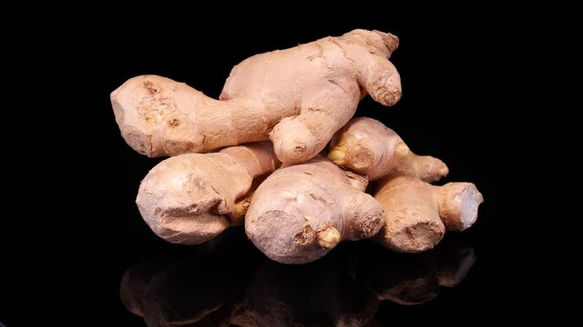 Ginger root on a black background. Fresh and organic ginger rotating on a black background