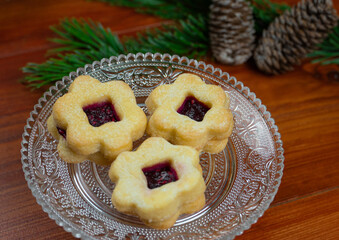 Delicious Christmas cookies on a glass dish. Fir branches and pine cones in the background.