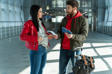 Young man and woman arguing with each other while holding tickets and standing at the airport. Problems concept