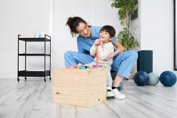 Therapist doing development activities with a little boy with cerebral palsy, having rehabilitation, learning . Training in medical care center. High quality photo. - obrazy, fototapety, plakaty
