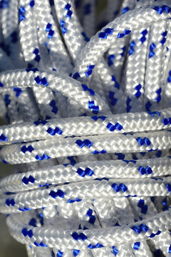 Close up and detailed view of a coiled plastic rope with white and blue fibers