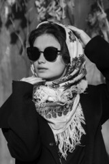 Portrait of a beautiful girl in black glasses and with an ethnic headscarf on her head