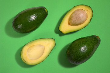 bright image fresh avocado fruit cutaway on green background, flat lay