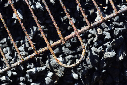 Close Up And Detail Shot Of A Greasy And Rusty Grill Grate Hanging Over Gray Charcoal In A Grill