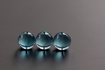Three crystal blue marbles in a line showing window reflections - stock photo.jpg