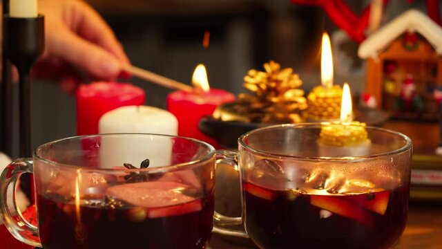 Mulled wine in glasses, gluhwein close-up. Hot red wine with apples, oranges, cinnamon, star anise. Winter traditional drinks. Christmas holidays and new year time, burning candles. 