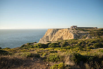 Naklejka premium Espichel's cape on portuguese coast. A beautiful landscape of Portugal. Blue sky and big cliff